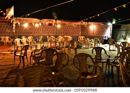 Plastic chairs in a mixed order stand on the ground in the Bedouin settlement in the evening Royalty-Free Stock Photo #1091029988