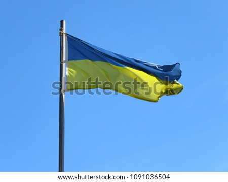 National flag of Ukraine on a flagpole in front of blue sky