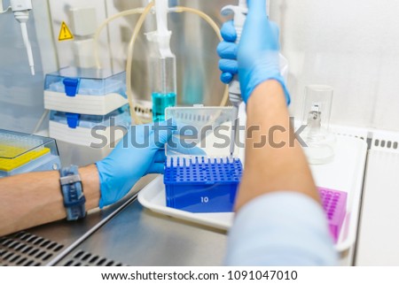 Scientist hands with dropper or pipette, examining samples and liquid. Microbiologist. Working in the fume hood. Researcher working with a Pipette in a Biochemistry Lab