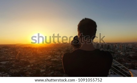 Silhouette of a photographer taking pictures on top of the build at sunset