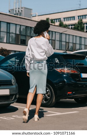 back view of african american businesswoman talking by smartphone on parking
