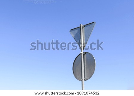 Blank directional road signs against a blue sky.

