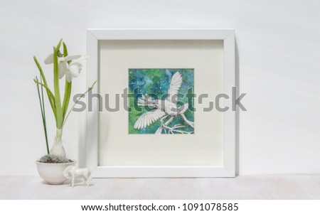 White interior display. Framed mixed media collage of Cockatoo parrot with wings outstretched. Snowdrop flower and horse ornament.