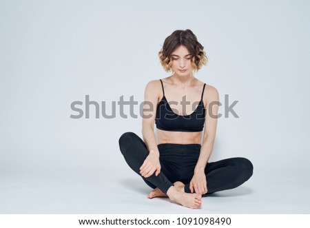  woman in leggings sits on the floor and is engaged in exercises                              