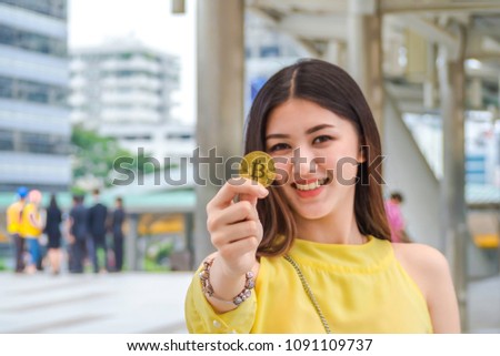  Shopping woman holding golden bitcoin to shopping online via smart phone at walkway.