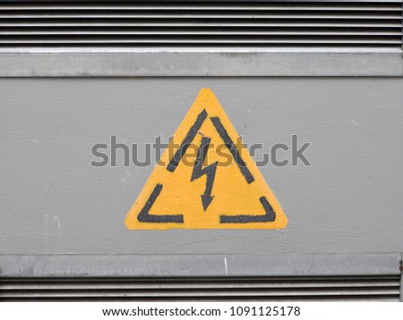 Yellow high voltage sign, depicted on a gray embossed metal surface.