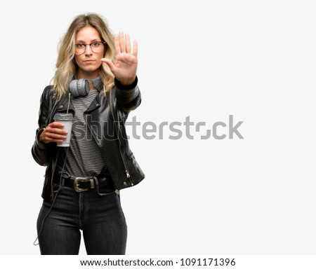 Young student woman with headphones annoyed with bad attitude making stop sign with hand, saying no, expressing security, defense or restriction, maybe pushing