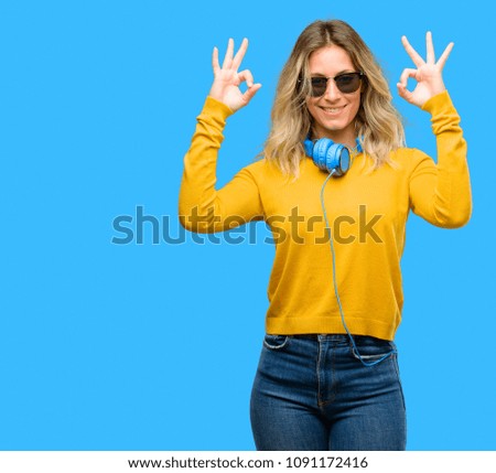 Young beautiful woman with headphones doing ok sign gesture with both hands expressing meditation and relaxation