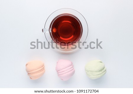 A cup of tea with colorful marshmallows in pastel colors on a neutral blue background. flat lay,top view.