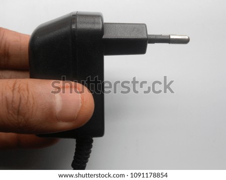 Hand of man holding black color 2 pin power plug adapter on white background