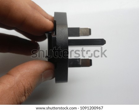 Hand of man holding black color 3 pin power plug adapter on white background