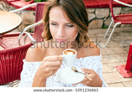 Beautiful blond woman having her morning espresso in summer terrace in Italy