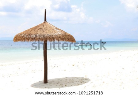 Closeup of a classical wooden beach umbrella and shadow on beautiful white sand beach with clear sea and lovely cloudy sky background in sunny day of summer.