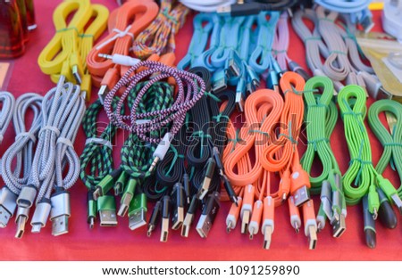 Mixed colors of clone usb cable charger on red table.