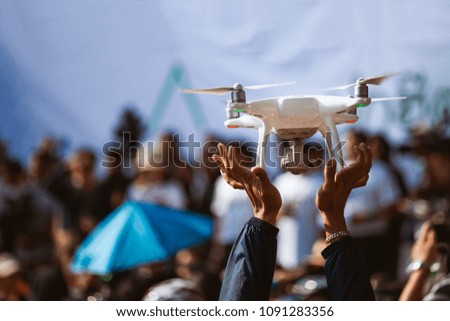 Young operator holding drone above crowd, before working with covering an event