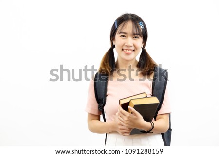 Smiling happy and casual Asian female college students holding pile of books with bag isolated over white background