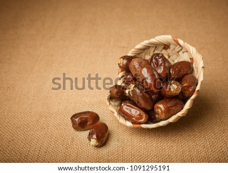 Few ripen finest quality Arabian dates in a handcrafted palm basket. Date is a staple fruit of middle east and africa. Royalty-Free Stock Photo #1091295191