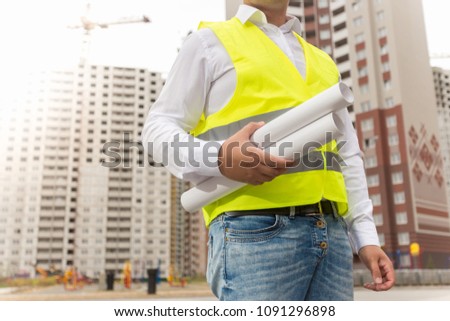 Closeup photo of male architect holding blueprints of new house