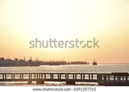 Sunrise on the harbor with boats and bride in dark sea