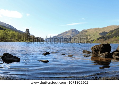 Beautiful Loch Eck, Scotland, UK on a clear sunny day showing water and mountains in a breath-taking view. A popular tourist attraction and holiday destination.