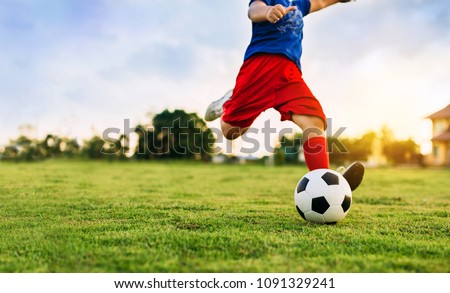 An action picture of a group of kid playing soccer football for exercise in community rural area under the sunset. Picture with copy space.