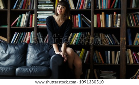 Brunette in black dress on background of books