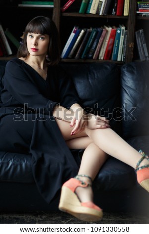 Brunette in black dress on background of books
