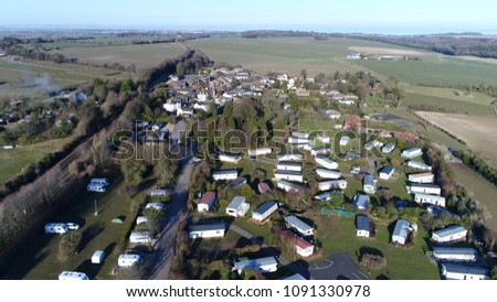 Aerial bird view picture of Farm Campsite and Holiday Park showing the long-term campsite that includes permanent and semi-permanent setups also showing caravans below