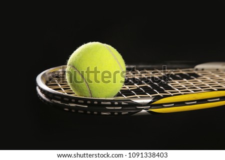 Racket for squash and a tennis ball on black a background.
