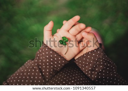 Four leaf green clover in small child's hands of happy young baby girl.