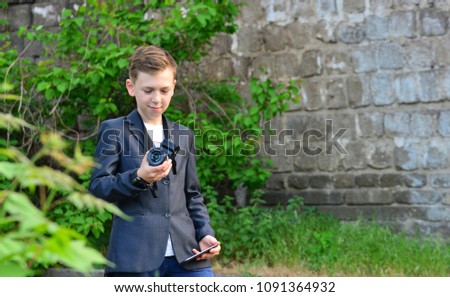 A boy with a camera does selfie on a smartphone, on the street