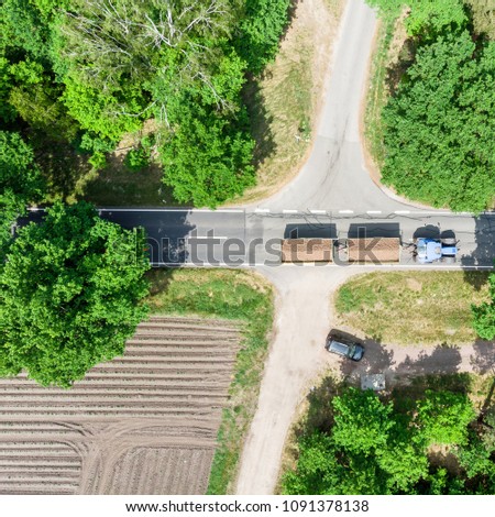 Aerial photo of a crossing in Germany near Celle over which a tractor with two loaded trailers drives, made with drone