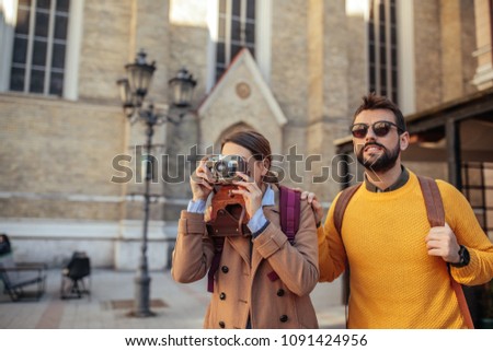 Shot of a young couple taking pictures while walking through the city