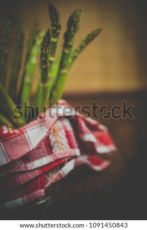 green asparagus in metal bowl with napkin on wooden background