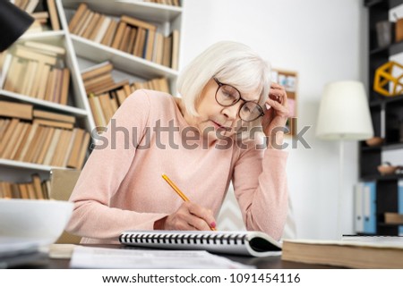 Too difficult. Uneasy mature woman touching head while writing