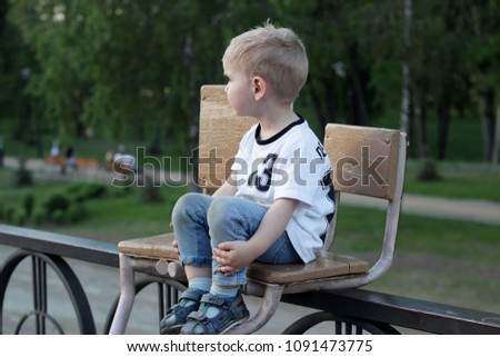 A close-up portrait of young 4-years old football player in football uniform with number 13 sitting and watching a final of match, confident and concentrated boy, child emotional portrait 
