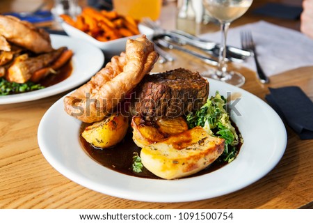 Vegetarian dinner with nut roast, potatoes, yorkshire pudding and gravy Royalty-Free Stock Photo #1091500754