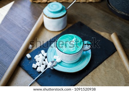 A cup of blue coffee and marshmallow on the restaurant table.