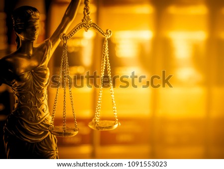 Legal law concept image, scales of justice lit by golden light.