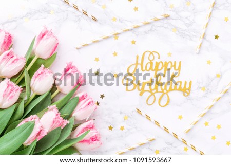 Pink tulips and gold Happy birthday letters with festive straws on white marble background. Spring and celebration concept. Copy space Top view. Horizontal