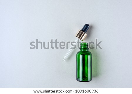 Minimalist photo of skin care, packaging for cosmetics. Green glass bottle with a pipette in pastel colors. Flat lay.