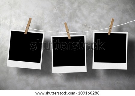 three photo paper attach to rope with clothes pins on old stone background