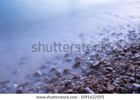 closeup picture of the sea wave on the gravel beach by long exposure make it smooth and soft.