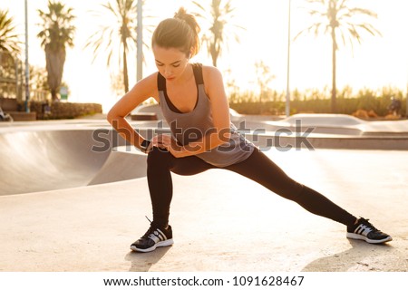 Photo of young amazing sports woman make stretching exercises outdoors on the street.