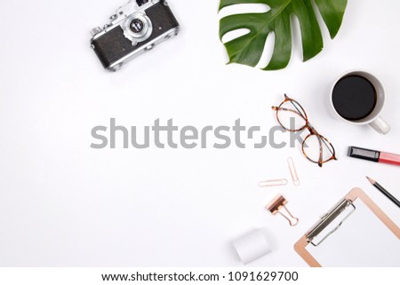 Travel blogger workspace with retro camera, coffee cup, notepad, glasses, lipstick and tropical palm leaf on white background.  Flat lay for bloggers, magazines, social media and artists. Top view.