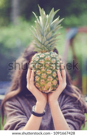 Girl holding pineapple in front of her face