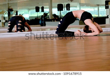 Young woman in black sportswear practicing yoga