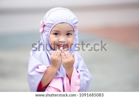 Muslim kid girl wearing Hijab praying Dua during Ramadan period. The concept is Islam,Dua,religion,worship and sin. Royalty-Free Stock Photo #1091685083
