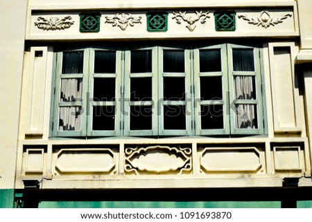 Front view of vintage Singapore shophouse with antique green shutters and vintage stonework in sunlight as vintage background 
