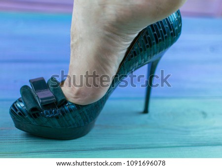 A man's leg in a woman's shoe with a heel. The concept of inappropriate shoe size, orientation disorders. Royalty-Free Stock Photo #1091696078